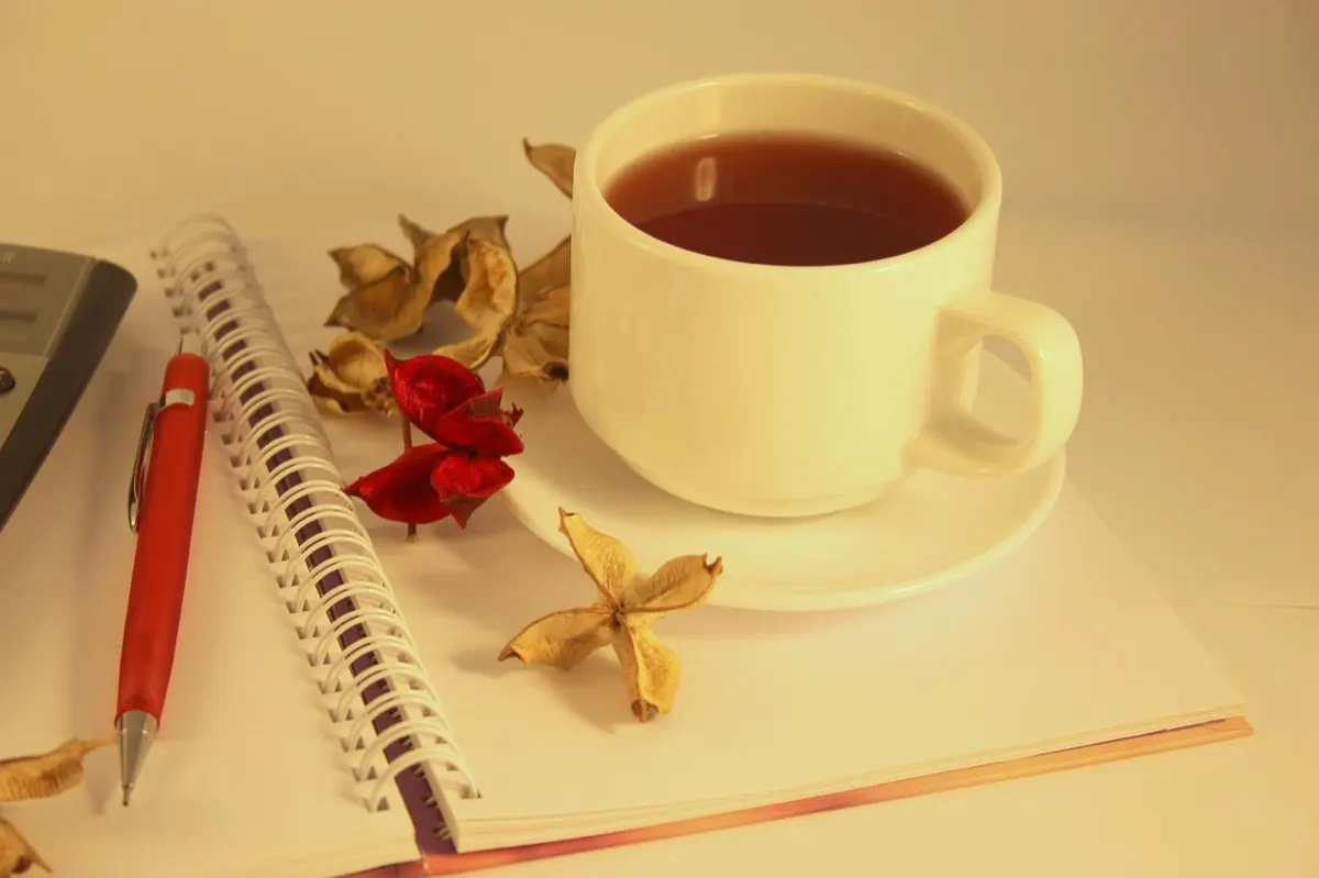 Carnet, stylo et tasse de thé sur une table lumineuse