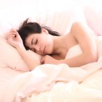 Femme dormant paisiblement dans un lit, illustrant l'importance du sommeil