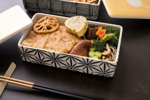 Bento box japonaise avec portions équilibrées de viande, légumes et accompagnements, illustrant la méthode Shokuiku